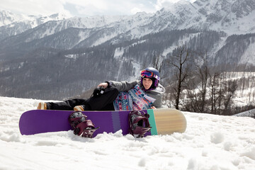 Girl snowboarder resting on the background of mountains
