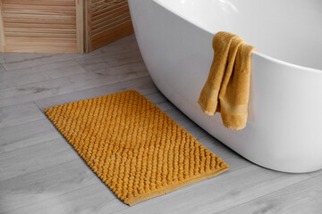Soft orange mat on floor near tub in bathroom. Interior design