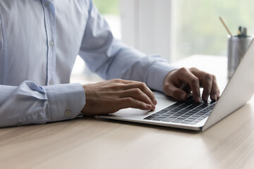 Close up young businessman entrepreneur manager typing on laptop keyboard, typing sending email or...