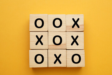 Tic tac toe cube set on yellow background, flat lay