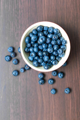 Blueberries in a red bowl on wooden table.