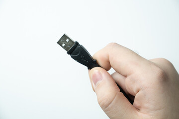Hand holding usb cable on white background