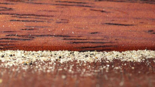 Sand being sucked by vacuum cleaner from old wooden floor. Macro.