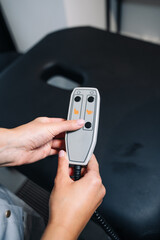 Beautiful female hands with manicure hold a remote control for adjusting the position from the massage table (bed) located in the SPA room. Presses the buttons.