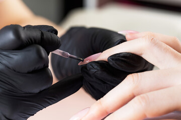 Manicure process in a beauty salon. The manicurist paints the nail with varnish.