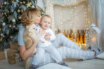 Child and mother in light pajamas on the background of a Christmas tree