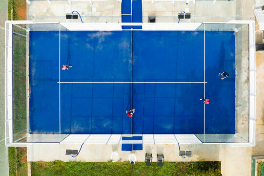 View From Above, Stunning Aerial View Of Some People Playing On A Blue Padel Court. Padel Is A Mix Between Tennis And Squash. It's Usually Played In Doubles On An Enclosed Court.