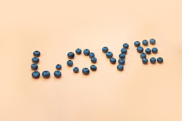 juicy, fresh blueberries on a beige background, the collected word "love", selective focus