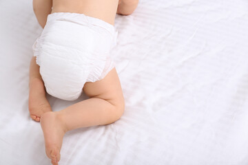 Fototapeta na wymiar Back view of cute baby in dry soft diaper on white bed, closeup. Space for text