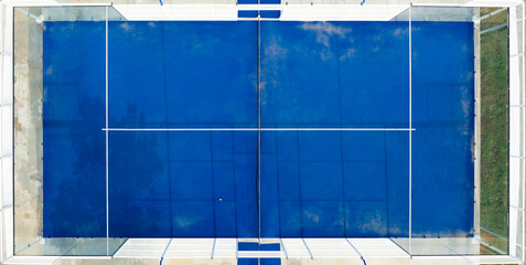 View from above, stunning aerial view of an empty blue padel court. Padel is a mix between Tennis and Squash. It's usually played in doubles on an enclosed court.