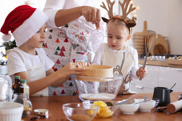 Mom and kids are in the kitchen preparing dough for Christmas cookies.