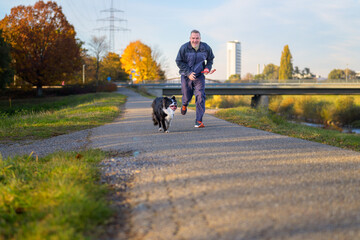 Fit energetic man racing his Border Collie along a footpath