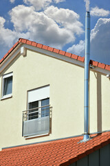 Schornstein, Außenkamin aus Edelstahl an der Fassade eines Wohnhauses