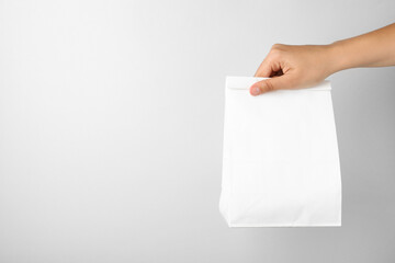 Woman holding paper bag on white background, closeup. Space for text