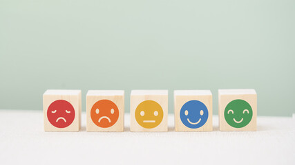 emotion face on wood block in soft focus,  on green background, customer review, feedback, rating,...