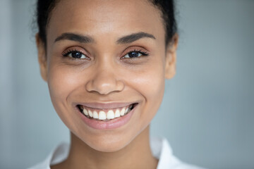 Head shot close up portrait attractive millennial african mixed race woman with perfect skin looking at camera, feeling satisfied with professional skincare spa cosmetology, salon procedures ad.