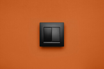 Black plastic light switch on orange background
