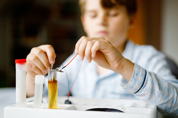 Closeup of hands of kid boy doing electric physical experiment as homework at home. Child study...