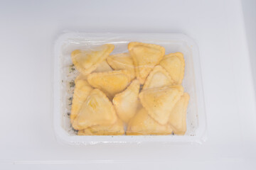 frozen fast food for deep-frying in vacuum packaging, triangles with meat, on a white background