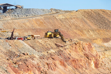 Mining trucks and machinery in Corta Atalaya open mine pit. Deep excavation of pyrite and extraction of minerals of cooper and gold in municipality of Minas de Riotinto, Huelva, Andalusia, Spain