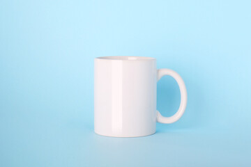 Blank white ceramic mug on light blue background