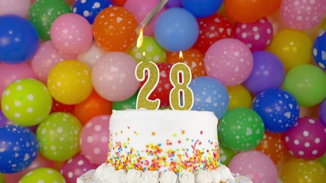 Birthday cake with candles number 28. Cake on a bright festive background of colorful balloons.