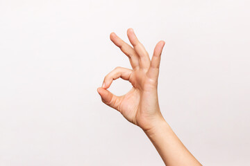 Female hand showing the ok gesture isolated on a white background. Okey hand sign - obrazy, fototapety, plakaty