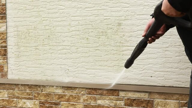 Man cleaning walls with high pressure power washer. Washing cladding walls house. High quality 4k footage