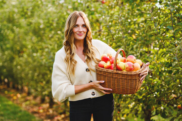 Happy school girl and beautiful mother with red apples in organic orchard. Happy woman and kid daughter picking ripe fruits from trees and having fun in garden. Harvest season for family.