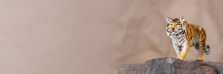 Tiger symbol of the Chinese new year 2022. Figurine of tiger on stone on pastel background. Copy space. Banner