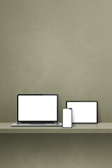 Laptop, mobile phone and digital tablet pc on green wall shelf. Vertical background