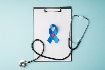 Top view photo of stethoscope clipboard with paper sheet blue silk ribbon and small red heart...