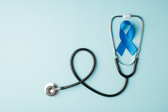 Top view photo of stethoscope and blue ribbon symbol of prostate cancer awareness on isolated pastel blue background with copyspace