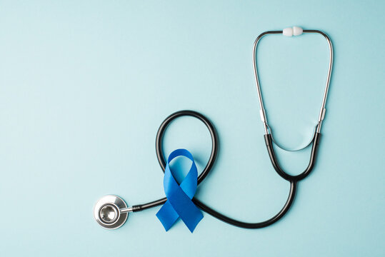 Top view photo of stethoscope and blue silk ribbon symbol of prostate cancer awareness on isolated pastel blue background with empty space