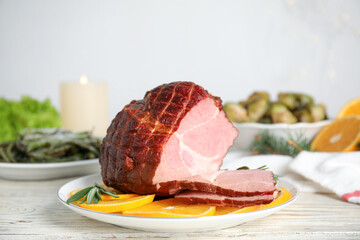 Delicious ham served with orange and rosemary on white wooden table