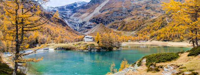 Panorama of the Palu Lake below Piz Palu glacier in Swiss Alps in autumn day with larch forest around and Piz Palu at the background, Canton of Grisons, Switzerland