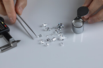 Close up of diamond expert's hand at workplace evaluating gemstones polished diamonds. High quality photo