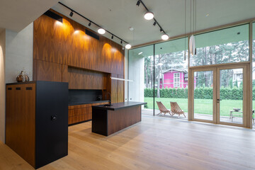 Modern interior of wooden kitchen in luxury private house. Garden view.