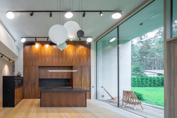 Modern interior of wooden kitchen in luxury private house. Garden view.