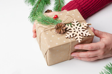 Decorated christmas gift box in female hands over white background