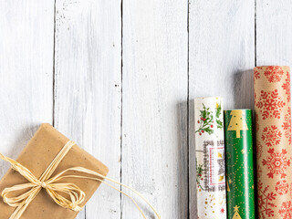 Weihnachtsgeschenk und Geschenkpapierrollen auf weißen Holzbrettern