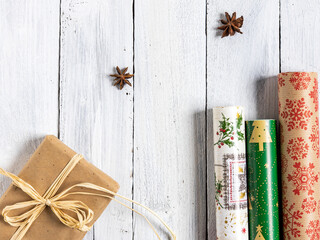 Weihnachtsgeschenk und Geschenkpapierrollen auf weißen Holzbrettern