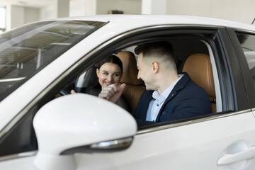 Married couple husband and wife sitting in a car in a car dealership. Test the car before buying.