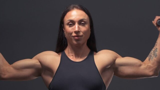 Muscular female bodybuilder woman workout arms: biceps and triceps in the gym. Sport and health care concept