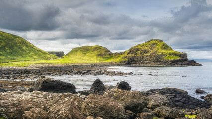 Tourists on the Giants Causeway trail with a view on rocky coastline and cliffs, Wild Atlantic Way, UNESCO world heritage, Northern Ireland
