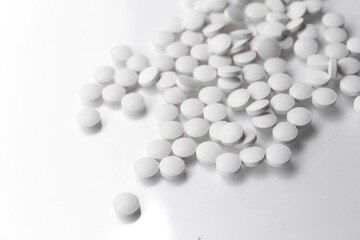 scattered white pills on white reflective background