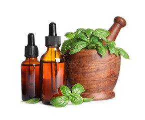 Bottles of basil essential oil near wooden mortar with leaves and pestle on white background