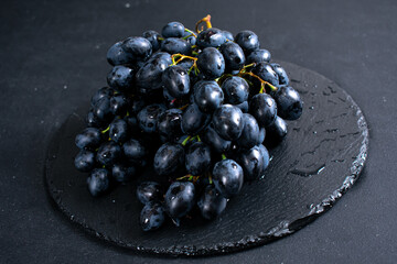 Brushes of black grapes on a dark background