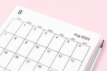 August 2022 calendar sheet with pen on pink background.