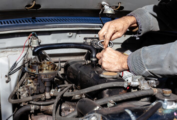 the mechanic uses a screwdriver to disassemble old engine. DIY repair. troubleshooting process. under the hood working